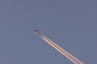 Boeing 767 jet cargo aircraft of FedEx flying in a blue sky with vapor trails or contrails behind,