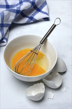 Whipped egg in shell with whisk, egg shells