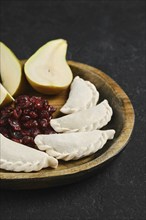 Close-up view of empanadas on a wooden platter, accompanied by a serving of sweet cranberries and