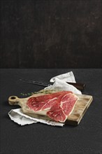 Thin slices of jamon iberico on a wooden cutting board, accompanied by a knife and a sprig of thyme