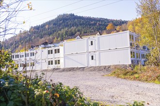 White container buildings embedded in hilly landscapes with autumn vegetation, refugee