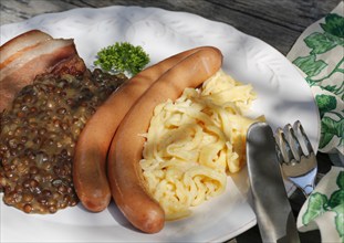 Swabian cuisine, lentils with spaetzle, pancetta and string sausages, meat arranged on a plate,