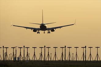 Boeing 737 jet passenger aircraft on approach to land at sunset over landing lights, London