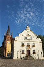 Historic church tower next to a baroque building in sunny weather with blue sky,