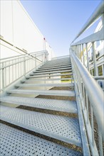 Metal stairs lead to a container building under a clear blue sky, refugee accommodation Beermiß,