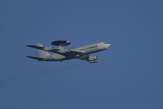 Boeing E-3 Sentry AWACS military aircraft of NATO flying in a blue sky, England, United Kingdom,