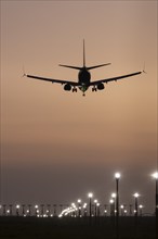 Boeing 737 jet passenger aircraft on approach to land at sunset over landing lights, London