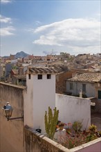 Mediterranean village with stone houses and green terraces under a slightly cloudy sky, Alcudia,