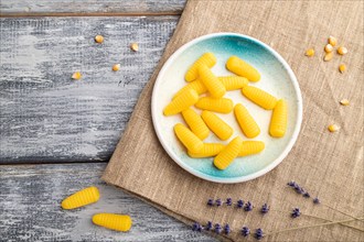 Jelly corn candies on gray wooden background and linen textile. close up, top view, flat lay