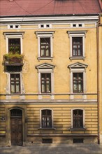 Old yellow painted roughcast with white trim architectural style building facade, Krackow, Poland,