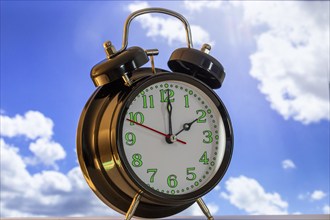 Symbolic image of the time change to summer time: close-up of an alarm clock in front of a blue sky