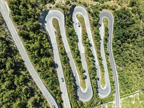 Mountain pass road with multiple hairpins, water pipeline, aerial view, drone shot. Valais,