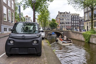 Mini car parked in the old town, Blauwburgwal canal, city centre of Amsterdam, Rocks Electric from