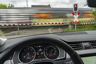 Car waiting at a level crossing, closed barriers, red warning light, traffic light and St Andrew's