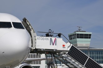 Airbus aircraft at check-in position with solar passenger stairs, control tower, satellite,