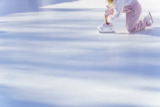 Girl lacing up her skates in an ice rink