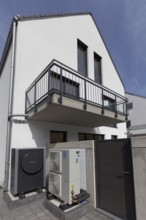 Outdoor units of an air-to-water heat pump in front of a newly built two-family house, heating and