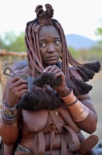 Himba woman combing her hair, Omuramba, Kaokoland, Kunene, Namibia, Africa