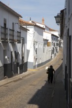 Woman walking along a quiet street in village of Jabugo, Sierra de Aracena, Huelva province, Spain,