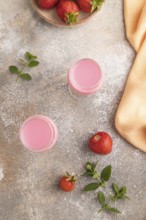 Sweet strawberry liqueur in glass on a gray concrete background and orange textile. top view, flat