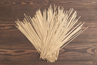 Japanese buckwheat soba noodles on brown wooden background. Top view, flat lay, close up