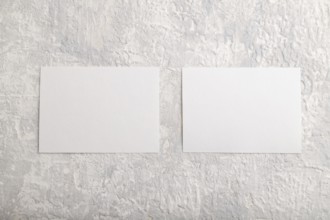 White paper business card, mockup on gray concrete background. Blank, flat lay, top view, still