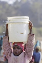 Girl carrying a heavy bucket of water on her head, Maraban Dare, 07/02/2024