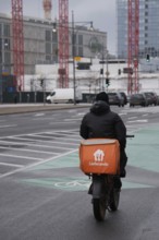 Delivery service cyclist riding on a cycle path, Berlin, Germany, Europe