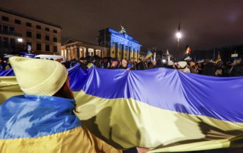 People demonstrate with a huge Ukrainian flag at the Brandenburg Gate on the anniversary of the