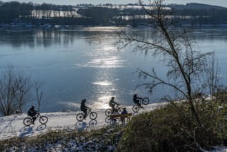 Winter in the Ruhr area, Lake Baldeney, snow-covered, partly frozen lake, walkers on the lakeside