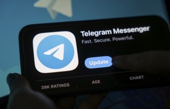 The social media Telegram messenger logo is being displayed on a smartphone screen and on a