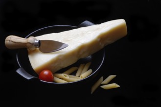 A piece of Parmesan cheese with cheese knife, pasta and tomatoes, Italy, Europe