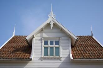 A traditional house with a red tiled roof and white wooden gable under a blue sky, Sandnes, Fylke