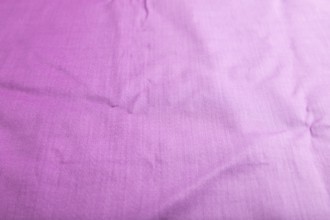 Fragment of smooth cotton purple tissue. Side view, natural textile background and texture