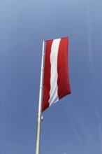 Österreichische Flagge vor blauem Himmel (Austrian flag in front of a blue sky)