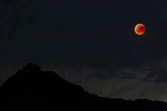 Complete lunar eclipse in front of mountains at night, full moon, Karwendel Mountains, Bavaria,