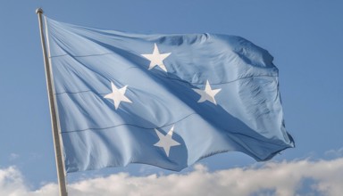 The flag of Micronesia, Pacific Islands, fluttering in the wind, isolated against a blue sky