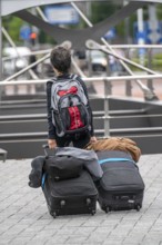 Travellers on their way to a river cruise ship at the quay of the Ij, transporting their luggage,