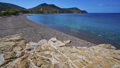 Beach with pebbles, mountains and clear blue water under a blue sky, Lambi beach, pebble beach,