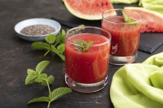 Watermelon juice with chia seeds and mint in glass on a black concrete background with green