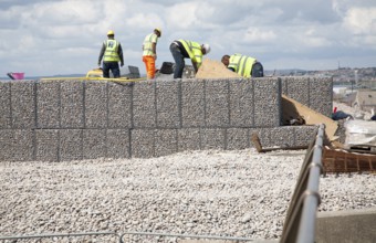 Repair work on steel mesh cages known as gabions which provide coastal defence at Chiswell, Isle of