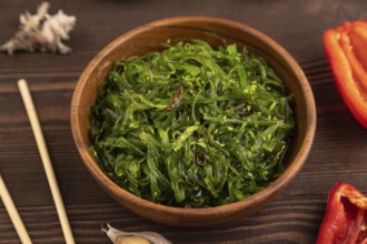 Chuka seaweed salad in wooden bowl on brown wooden background. Side view, close up, selective focus