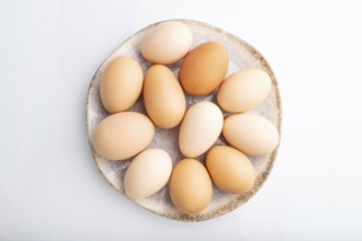 Pile of colored chicken eggs on plate isolated on white background. top view, flat lay, close up