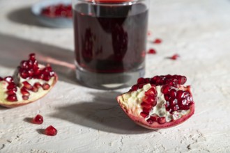 Glass of pomegranate juice on a white concrete background. Hard light, contrast. Side view, close