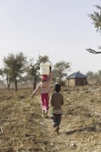 Girl carrying a heavy bucket of water on her head, Maraban Dare, 07/02/2024