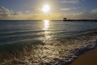 Sunset on the beach with a view of a jetty, breaking waves and shining sunbeams, Dominicus beach,