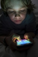 A boy plays computer games on a mobile phone, smartphone