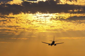 Passenger plane in front of a cloudy evening sky, sunset, sunbeams, Baden-Württemberg, Germany,