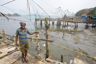 Indian fisherman standing at Chinese fishing nets, behind the Arabian Sea, Kochi, Kerala, India,