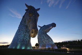 Two giant illuminated horse sculptures called Kelpies rise from the water at dusk, Forth and Clyde